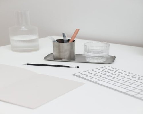Open notebook with a pen and a glass of water on a desk